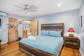 Ein Schlafzimmer mit einem hölzernen Bett, einem Deckenventilator, einem Nachttisch mit Lampe und einem Holzschrank.