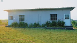 Un bâtiment d’un seul étage, doté d’un toit plat, de deux fenêtres grillagées et d’une porte surmontée d’un petit auvent.