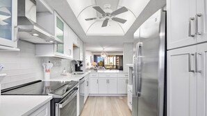 Een moderne keuken met witte kasten, roestvrijstalen apparatuur en een centraal kookeiland.