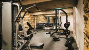 Ein Fitnessstudio mit Gewichthebersportgeräten, Bänken und Kurzhanteln.