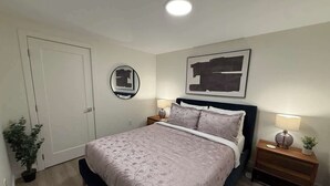 Ein Schlafzimmer mit einem Bett, Nachttischen, einer Wanduhr und einer Tür.