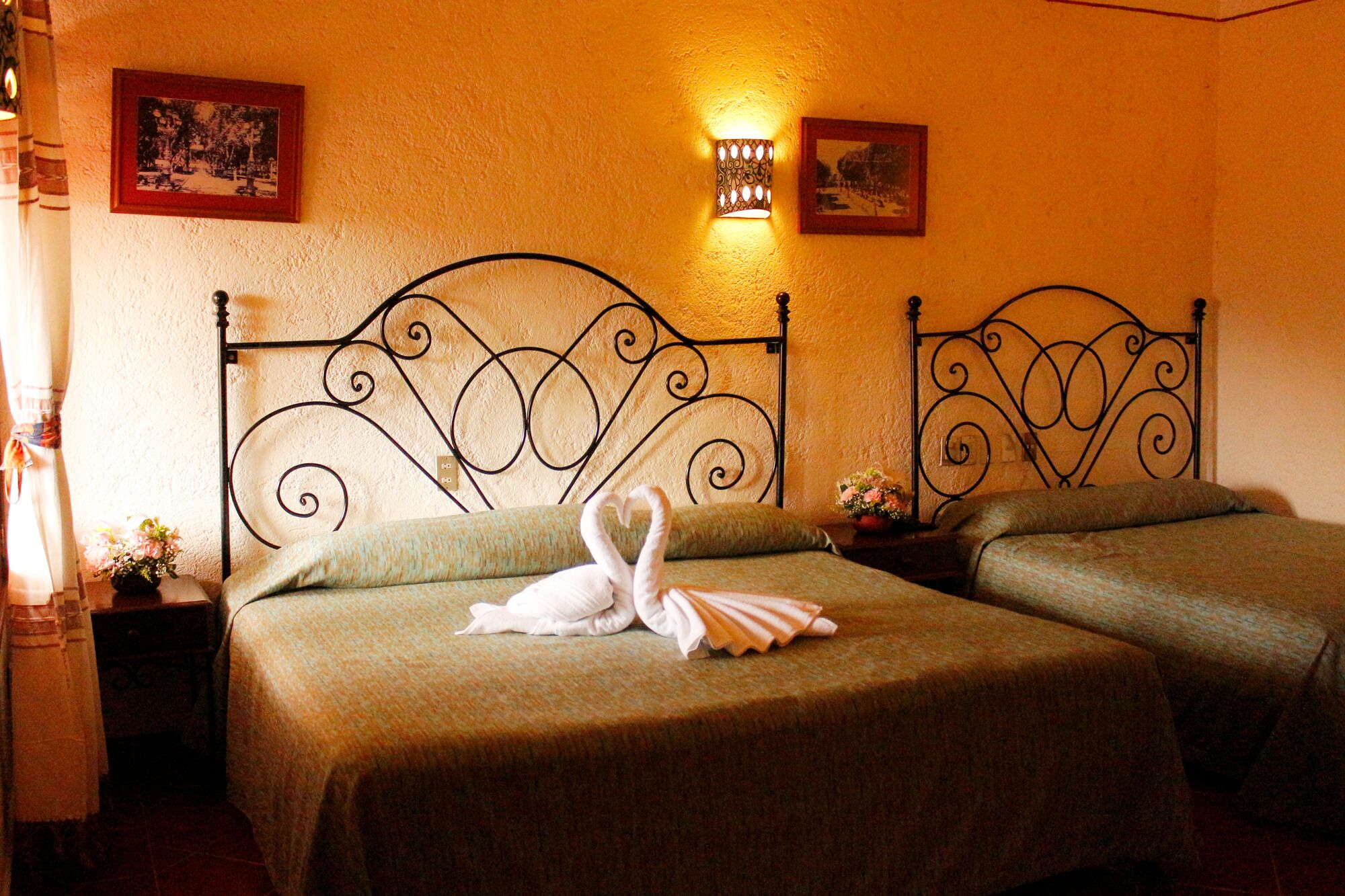 A hotel room with two beds, each with a decorative headboard and a wall-mounted light fixture.