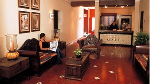 A hotel lobby with a reception desk, seating area, and artwork on the walls. - HOTEL MAELA (Oaxaca)
