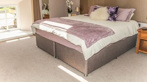 A bedroom with a large bed, a bedside table, a lamp, and a window with curtains. - The Granary (Durham)