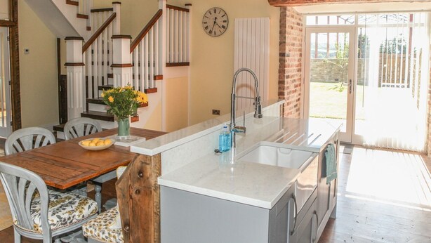A kitchen with a central island, white cabinets, and a stainless steel sink. - The Granary (Durham)
