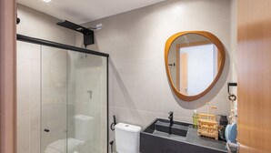 A modern bathroom with a glass shower enclosure, a round mirror, and a black countertop with a sink. - House w/ Pool and Barbecue Grill Sgt0000 (Porto de Pedras)