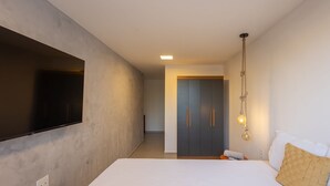 A modern hotel room with a large bed, a flat-screen TV mounted on the wall, a wardrobe with a mirror, and a hanging light fixture. - House w/ Pool and Barbecue Grill Sgt0000 (Porto de Pedras)