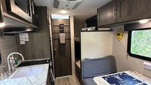 Ein kompaktes Wohnmobil-Interieur mit einer Küchenzeile, einer kleinen Sitzecke und einem Fenster.