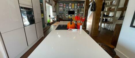 A modern kitchen with a central island, wooden beams, and a wall of framed pictures.