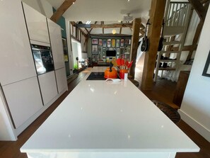 Een moderne keuken met een centraal eiland, houten balken en een wand met ingekaderde foto's.