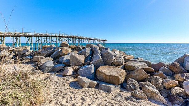 A pier extending into the sea with large rocks in the foreground. - Paradise Found - Pet friendly home with Ocean & Marsh Views! (Carolina Beach)