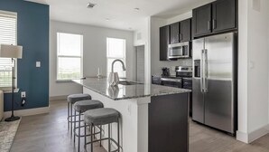 Una cocina moderna con una isla central, electrodomésticos de acero inoxidable y una zona de asientos con taburetes de bar.