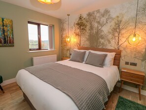 A bedroom with a large bed, a window, a wall mural, and two wall-mounted lights. - Stackyard (Durham)