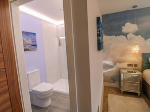A modern bathroom with a toilet, shower, and a painting of a sunset. - Stackyard (Durham)