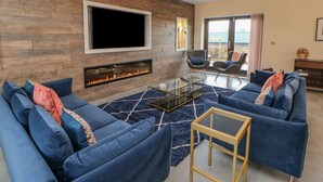 Un salon moderne avec une cheminée, des canapés bleus et une table basse en verre.