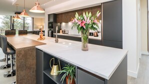 Una cucina moderna con isola centrale, illuminazione a sospensione e un vaso di fiori.