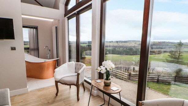 Un interno moderno con una grande finestra, una vasca da bagno e vista sulla campagna.