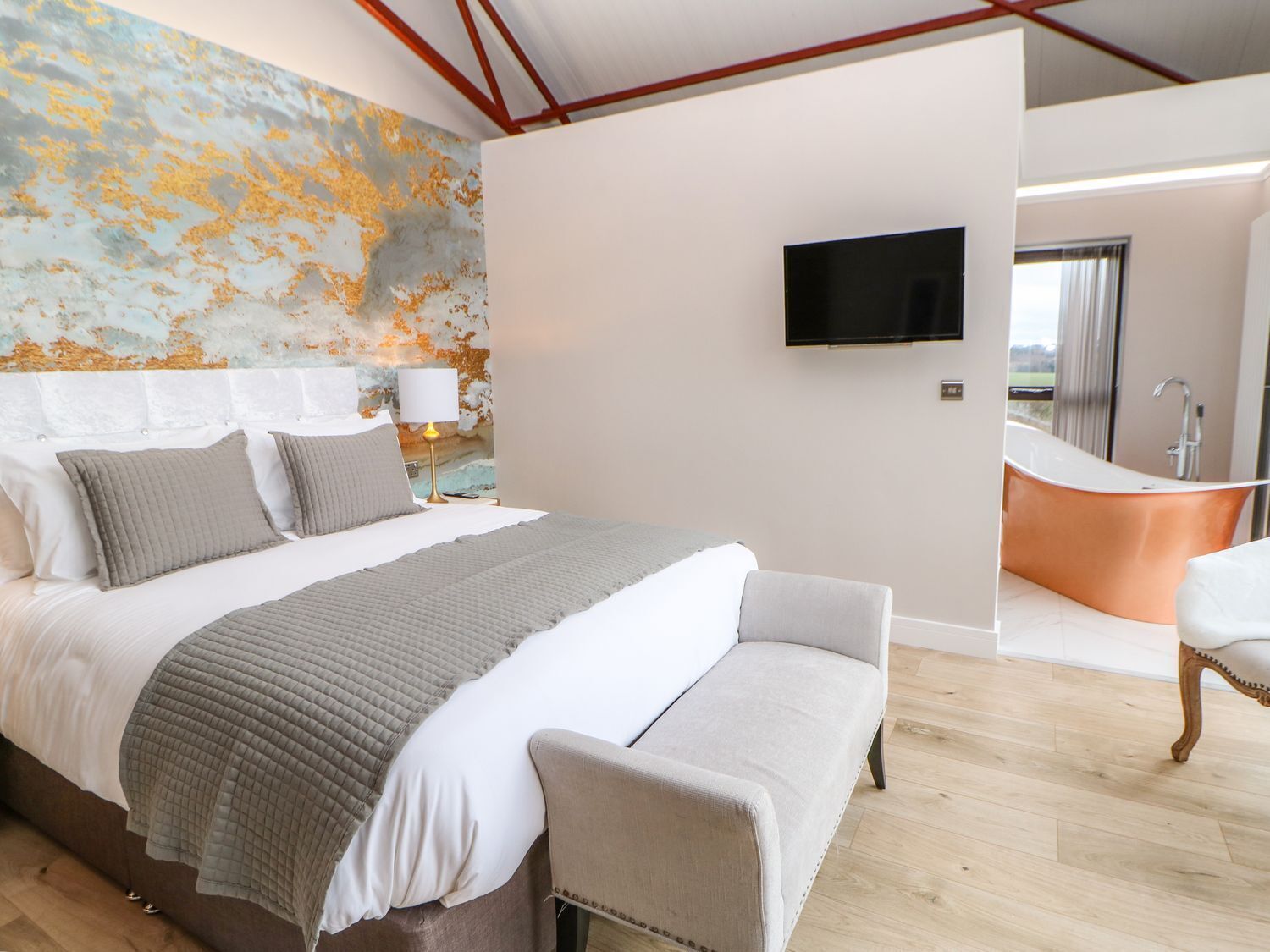 A modern bedroom with a large bed, a television, and a bathtub.