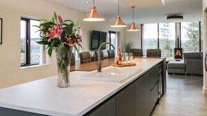 Una cucina moderna con isola centrale, illuminazione a sospensione e vista sull'esterno.