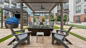 Une terrasse extérieure équipée d’un barbecue, de chaises et d’une table.