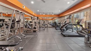 Une salle de sport équipée de divers appareils d’exercice, notamment des tapis de course et des appareils de musculation, disposés en rangées.