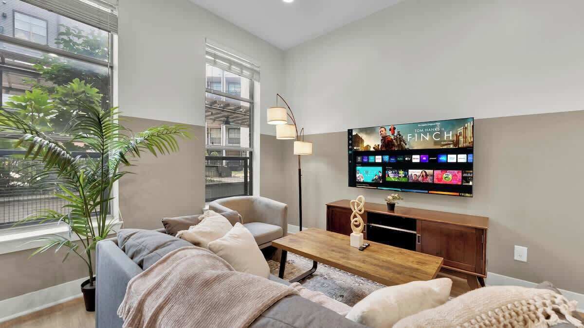 A modern living room with a sofa, coffee table, and a flat-screen TV mounted on the wall.