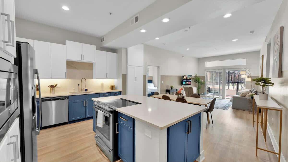 A modern kitchen with white and blue cabinets, stainless steel appliances, and a central island.