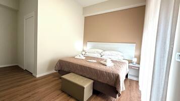 A bedroom with a bed, bedside tables, a nightstand, and a bench.