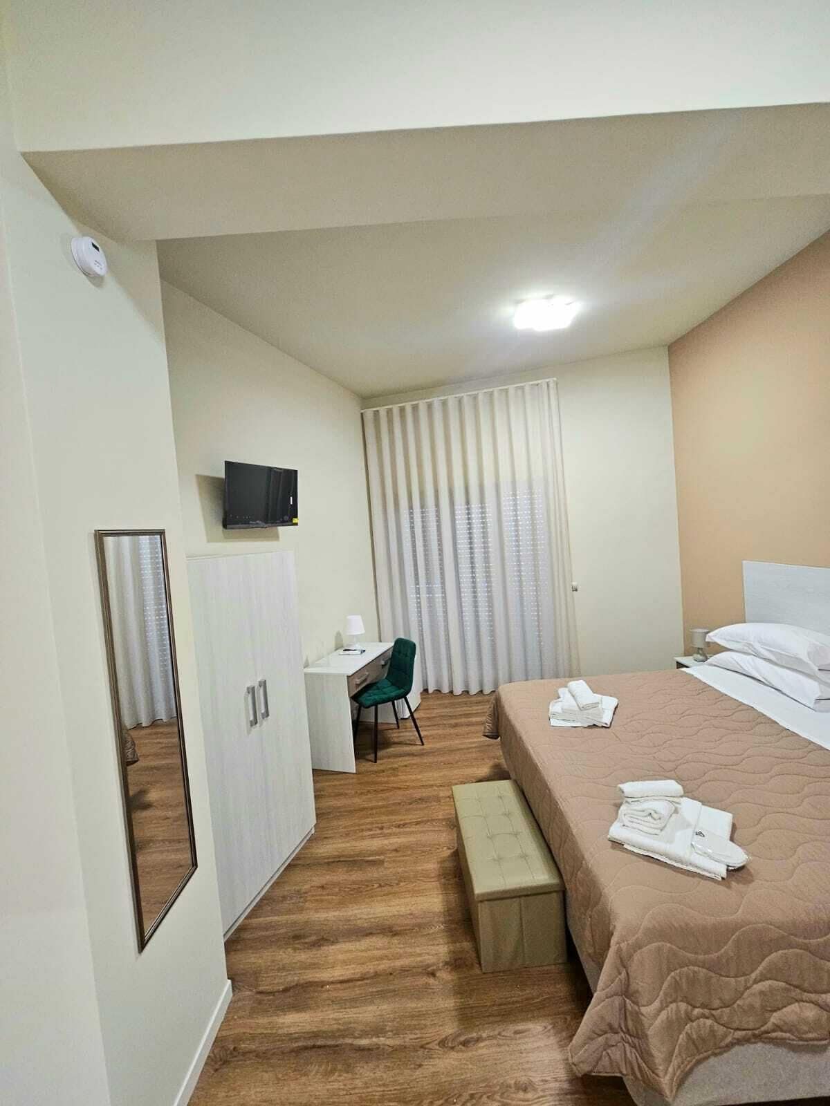Una habitación de hotel con cama, escritorio, silla, televisor y armario.