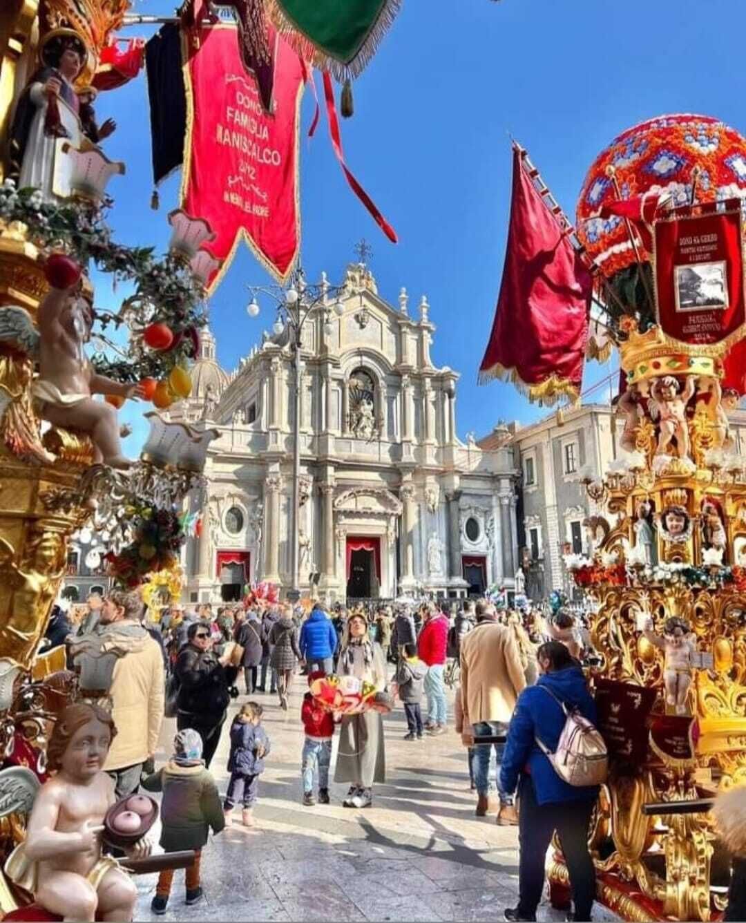Escena de calle concurrida con una iglesia destacada al fondo, rodeada de decoraciones festivas y una multitud de gente.