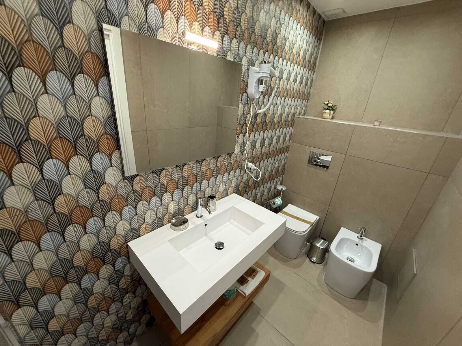A modern bathroom with a large mirror, a white sink, and a shower area.