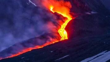 A volcanic eruption with lava flowing down the side of a mountain.