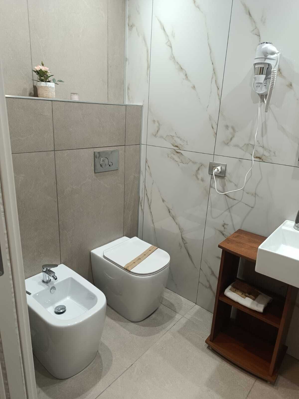 A modern bathroom with a bidet, a toilet, a sink, and a shower.