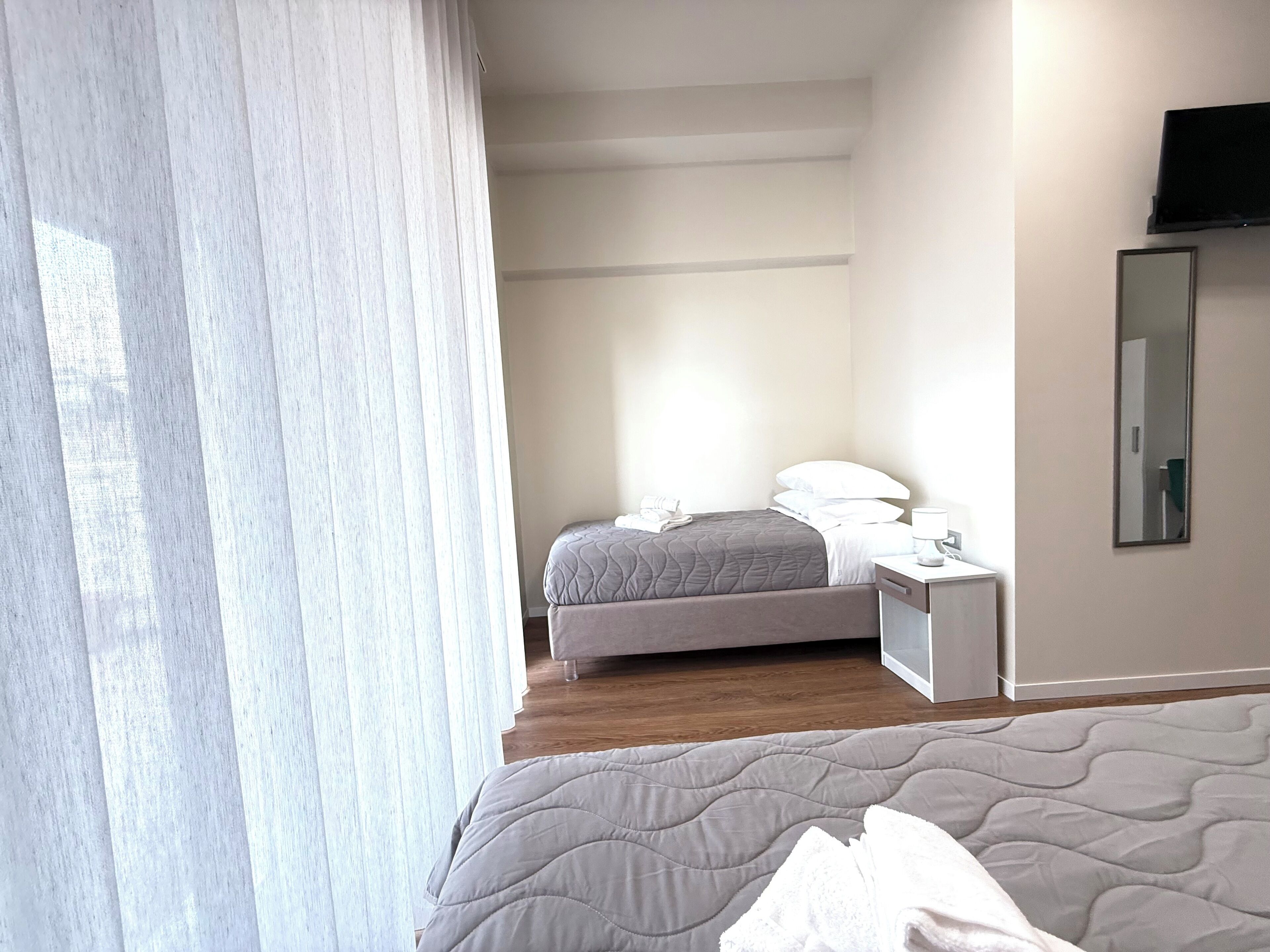 A hotel room with a bed, bedside table, and a TV mounted on the wall.