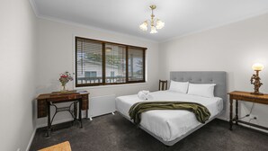 Ein Schlafzimmer mit einem Bett, einem Schreibtisch, einem Stuhl, einer Lampe und einem Fenster mit Jalousien.