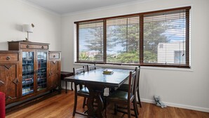 Ein Essbereich mit einem Holztisch und Stühlen, einem Schrank mit Glastüren und einem großen Fenster mit Jalousien.
