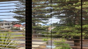 Ein Wohngebiet mit Häusern, einer Straße und Blick auf das Meer durch Bäume.