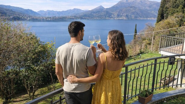 Una pareja contemplando un lago con montañas al fondo.