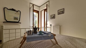 Un dormitorio con cama, ventana, radiador y espejo.