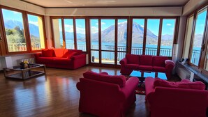 Una habitación amplia con ventanas grandes, un sofá rojo y una mesa de centro.