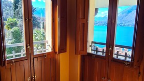 Una habitación con suelo de madera, ventanas amplias con vistas a un paisaje montañoso y puertas de madera.