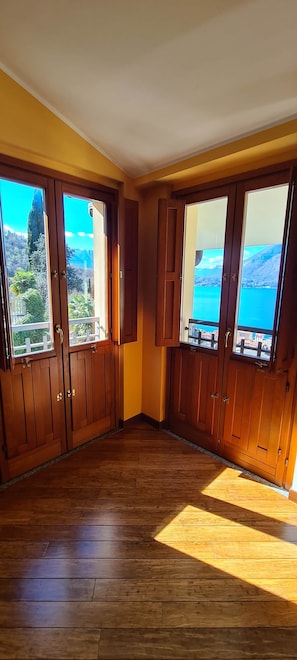Une pièce dotée d’un plancher en bois, de grandes fenêtres offrant une vue sur un paysage montagneux et de portes en bois.