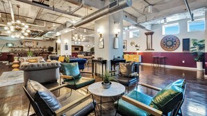 A spacious lounge area with leather sofas, a round table, and a dartboard on the wall. - Cozy Penthouse Apt w/Free Valet, Gym, Pool, View (Dallas)