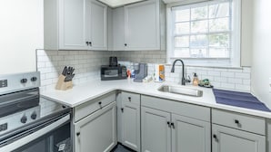 A kitchen with white cabinets, a microwave, a coffee maker, and a sink. - Suite B at Blue Sky Terrace (Columbus)