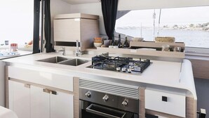 Cocina moderna con estufa a gas, pileta y horno, con vista al agua.