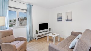 Een moderne woonkamer met een bank, een salontafel, een televisie en een raam met gordijnen.