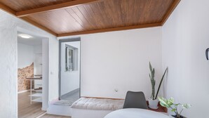 Een kamer met een bed, een stoel, een potplant en een trap naar een andere kamer.