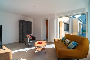 Ein Wohnzimmer mit einer Couch, einem Tisch, einem Sessel und einem Schrank.