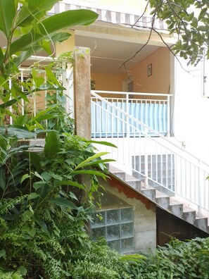 A staircase leading to a balcony with a railing, surrounded by dense greenery. - LET THE SONG OF THE BIRDS LULLE YOU TO SLEEP (Sainte-Luce)