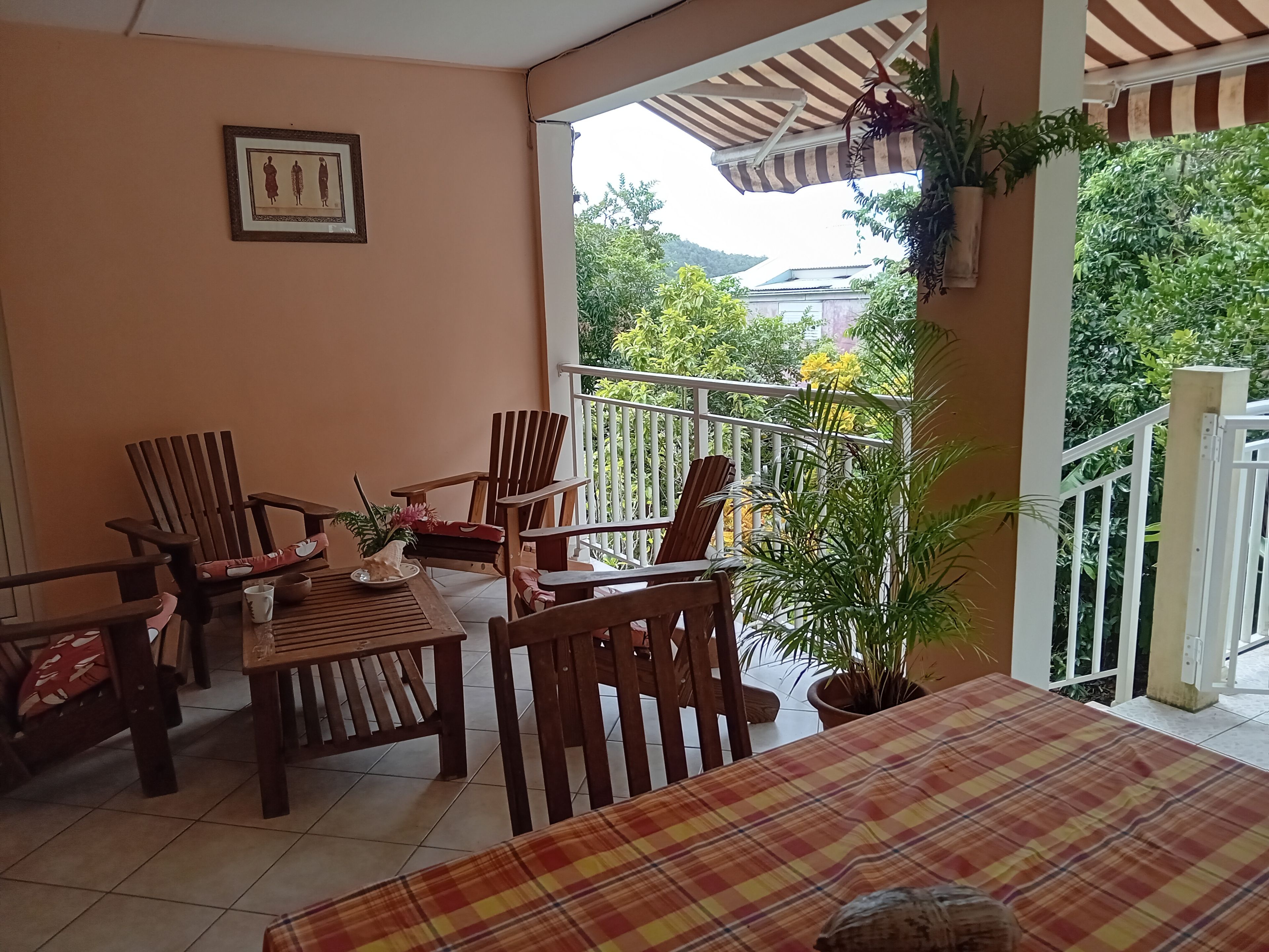 A balcony with wooden furniture, a checkered tablecloth, and potted plants.